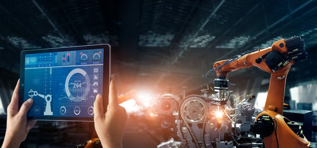 Bras robot orange en production, étincelles de soudure dans un atelier