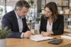 Un dirigeant et une conseillère examinent un contrat de cession près d’une calculatrice à écran vierge
